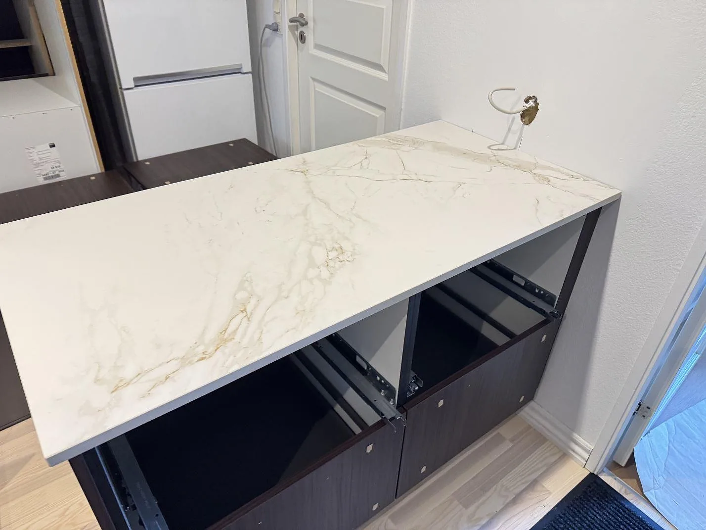 Halvö i matt Dekton Entzo med genomgående guldbeige ådring i ett kök under montering i Hedehusene.