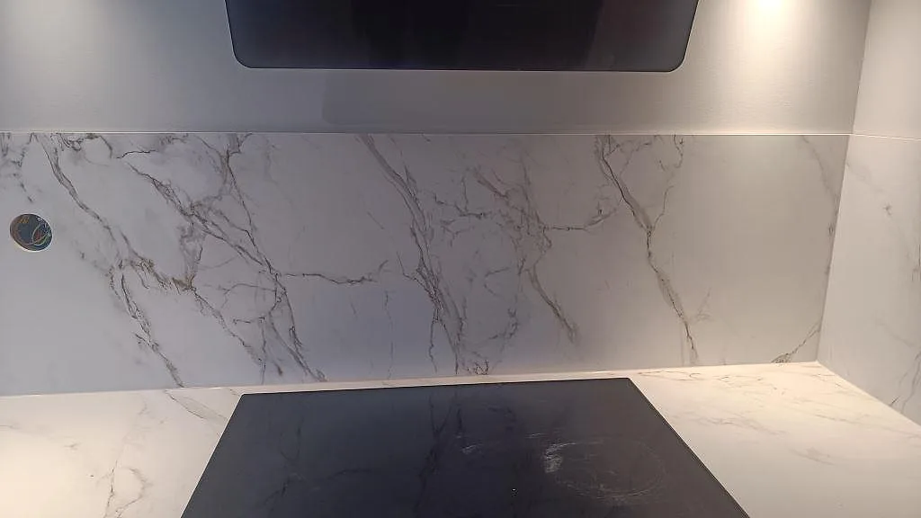 Detalj av induktionshäll och stänkskydd i matt Dekton Entzo med grå ådring i ett kök i Jönköping.