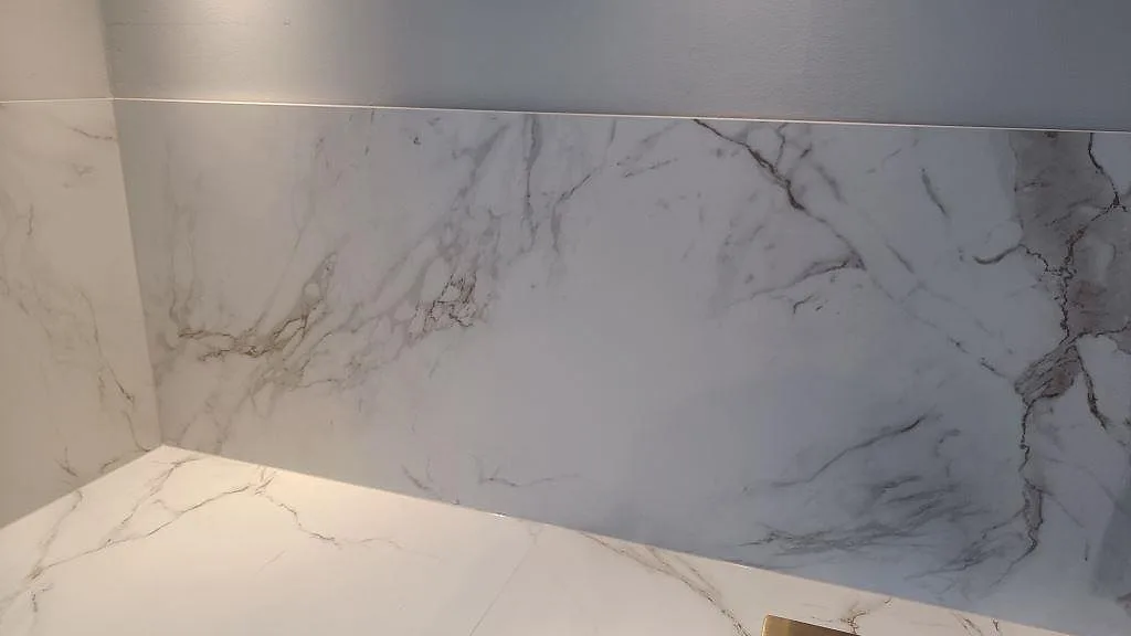 Hörndetalj av matt Dekton Entzo där bänkskiva och stänkskydd möts i ett kök i Jönköping.