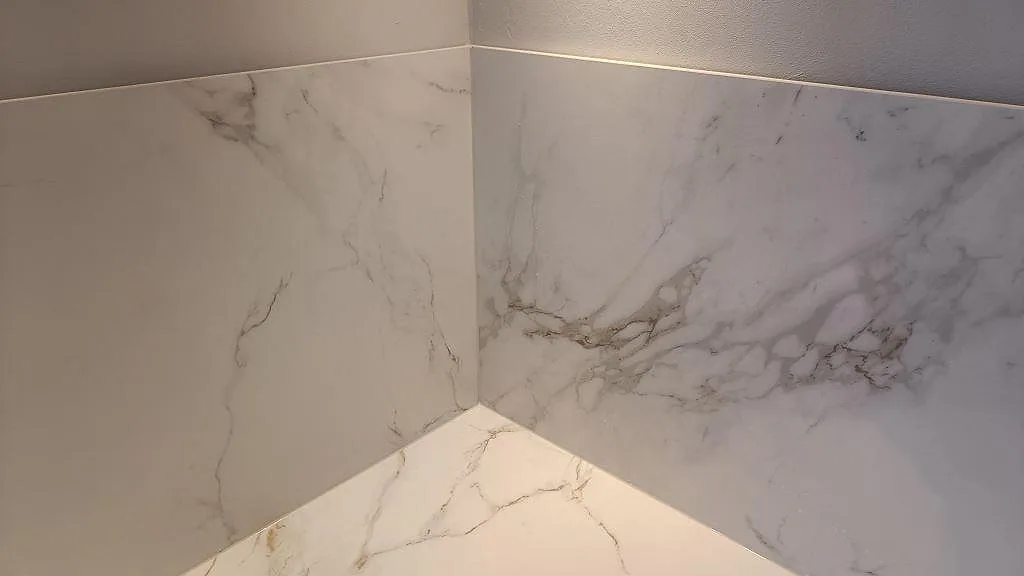 Marmorerat hörn med matt Dekton Entzo som bänkskiva och väggskiva under köksmontering i Jönköping.