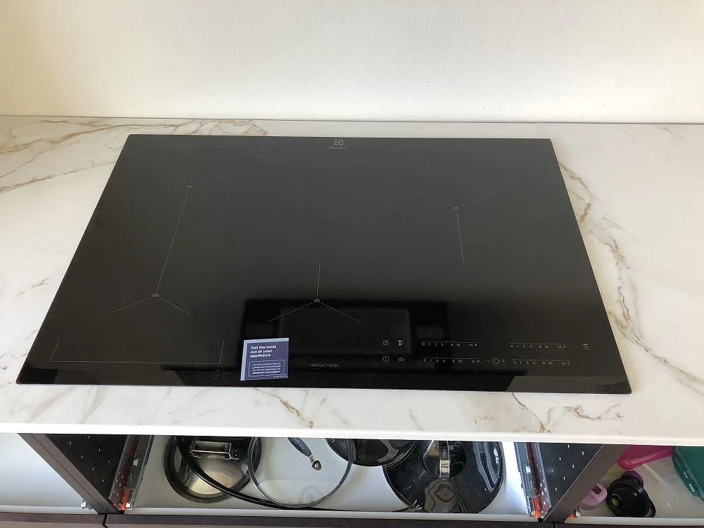 Infälld svart induktionshäll i en matt vit Dekton Entzo köksbänkskiva med Calacatta-ådring i ett kök i Kastrup.