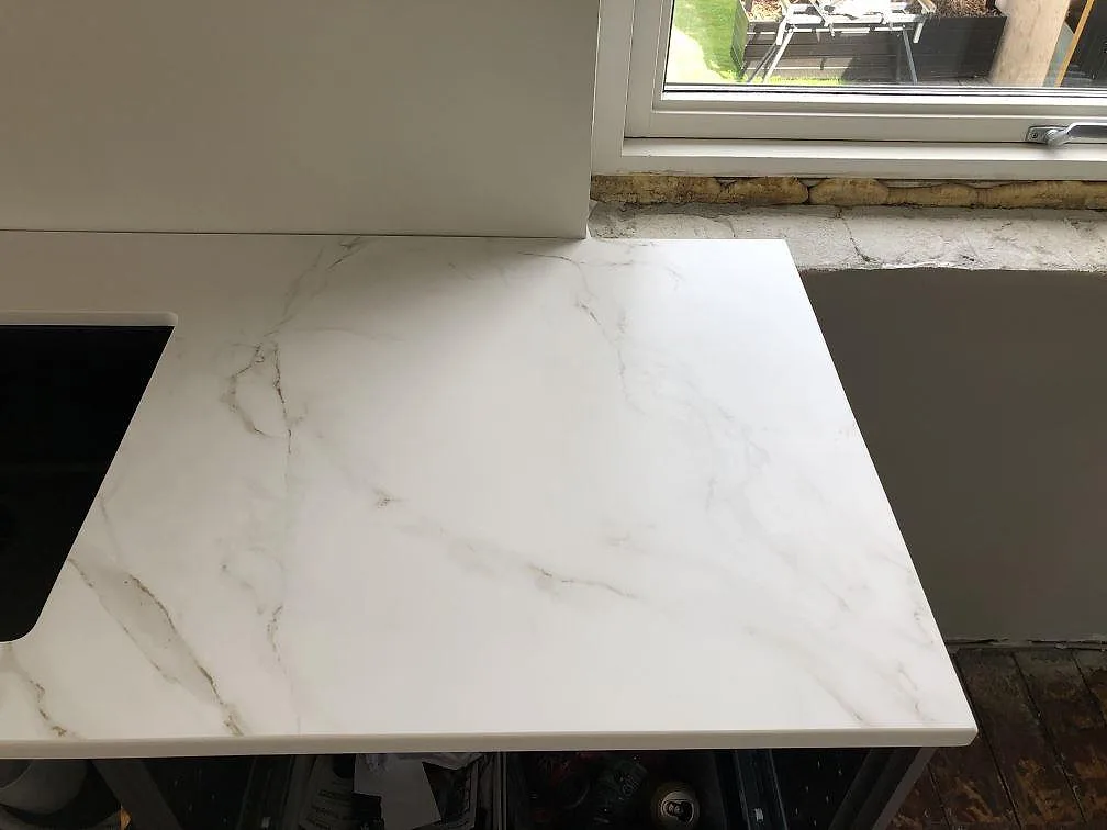 Bänkskiveände i vit Dekton Entzo med matt yta och mjuk grå ådring intill ett fönster i ett kök i Kastrup.