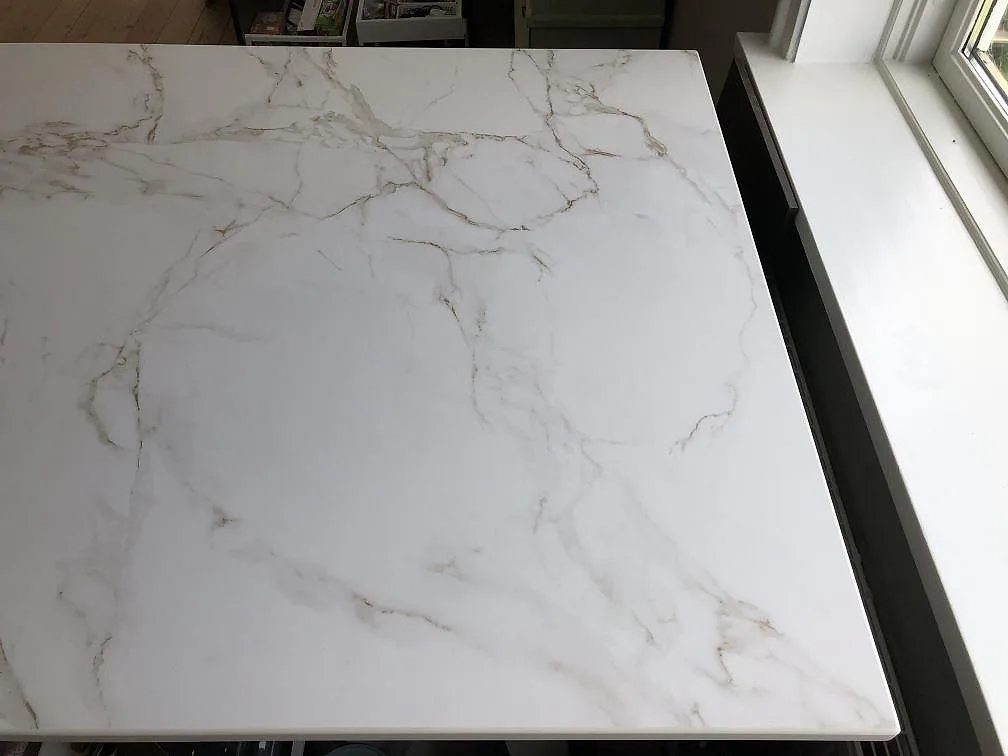 Köksö med ovanyta i matt vit Dekton Entzo och markant grå och guldaktig ådring i ett kök i Kastrup.