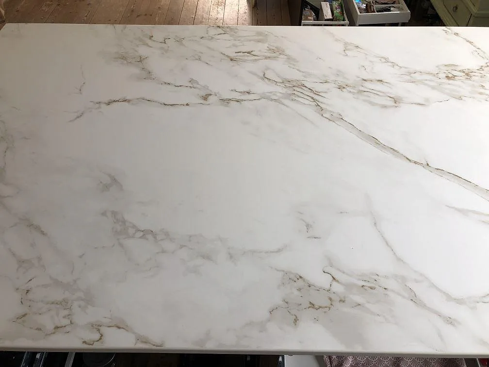 Ovanyta på köksö i matt vit Dekton Entzo med genomgående grå och guldaktig ådring i ett kök i Kastrup.