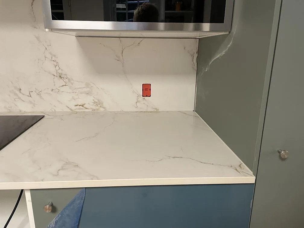 Höger arbetsyta i matt Dekton Entzo keramik med vit marmorlik ådring och blå köksfront i København K.