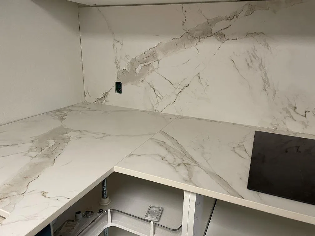 L-format kök med matt Dekton Entzo bänkskiva och matchande väggbeklädnad i keramik under montering i København K.