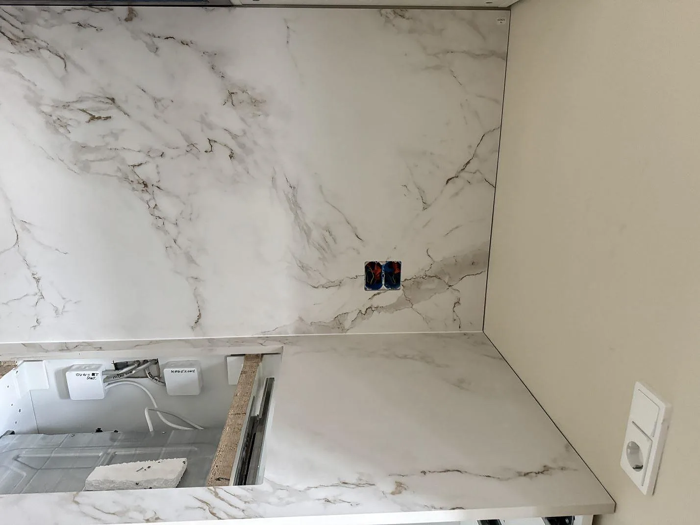Närbild på stänkskydd och bänkskiva i matt Dekton Entzo med sammanhängande ådring bakom arbetsytan i København NV.