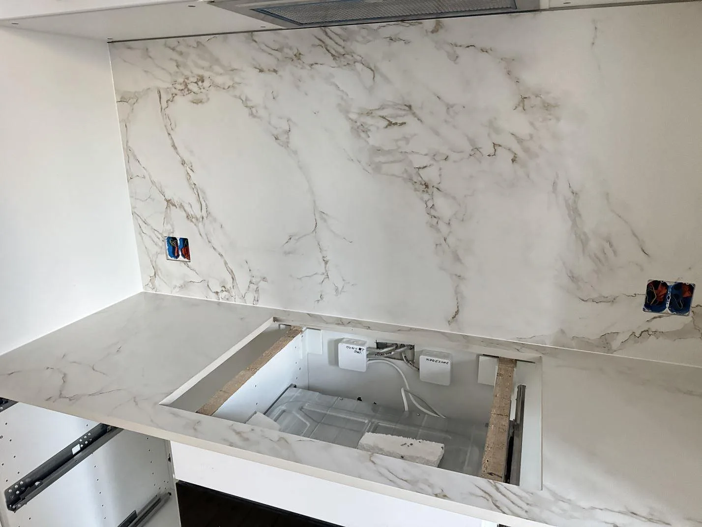 Bänkskiva och stänkskydd i matt Dekton Entzo med grå och varma ådringar, hälluttag och väggbeklädnad i ett kök i København NV.