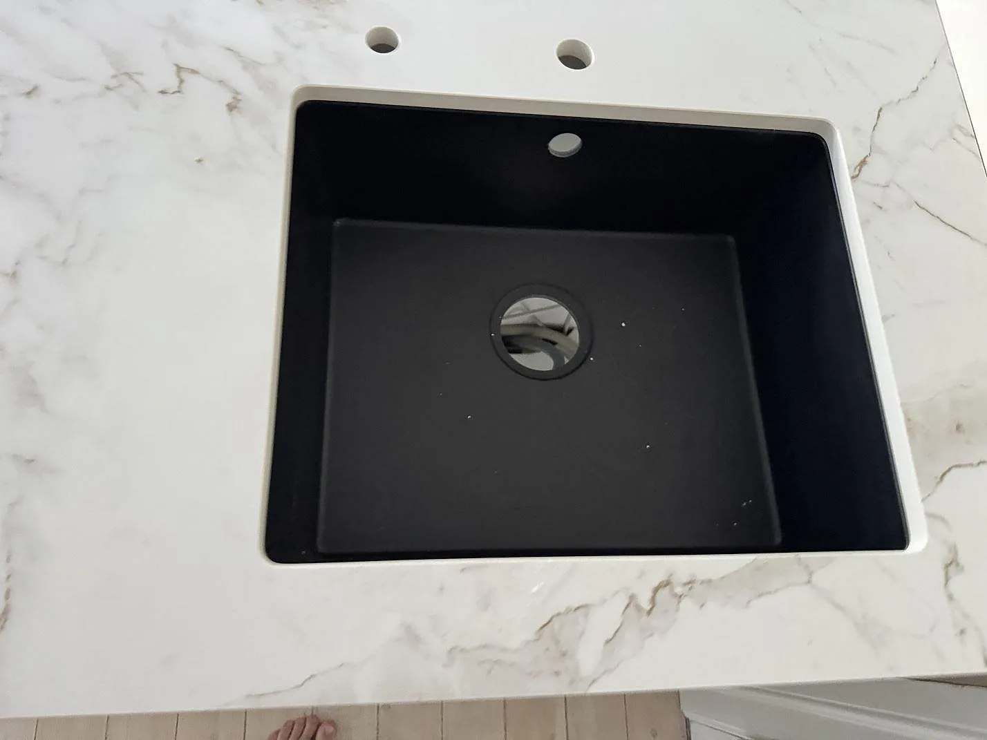 Ovanifrån syns den svarta diskhon i en ljus matt Dekton Entzo köksbänkskiva med grå ådring i København NV.