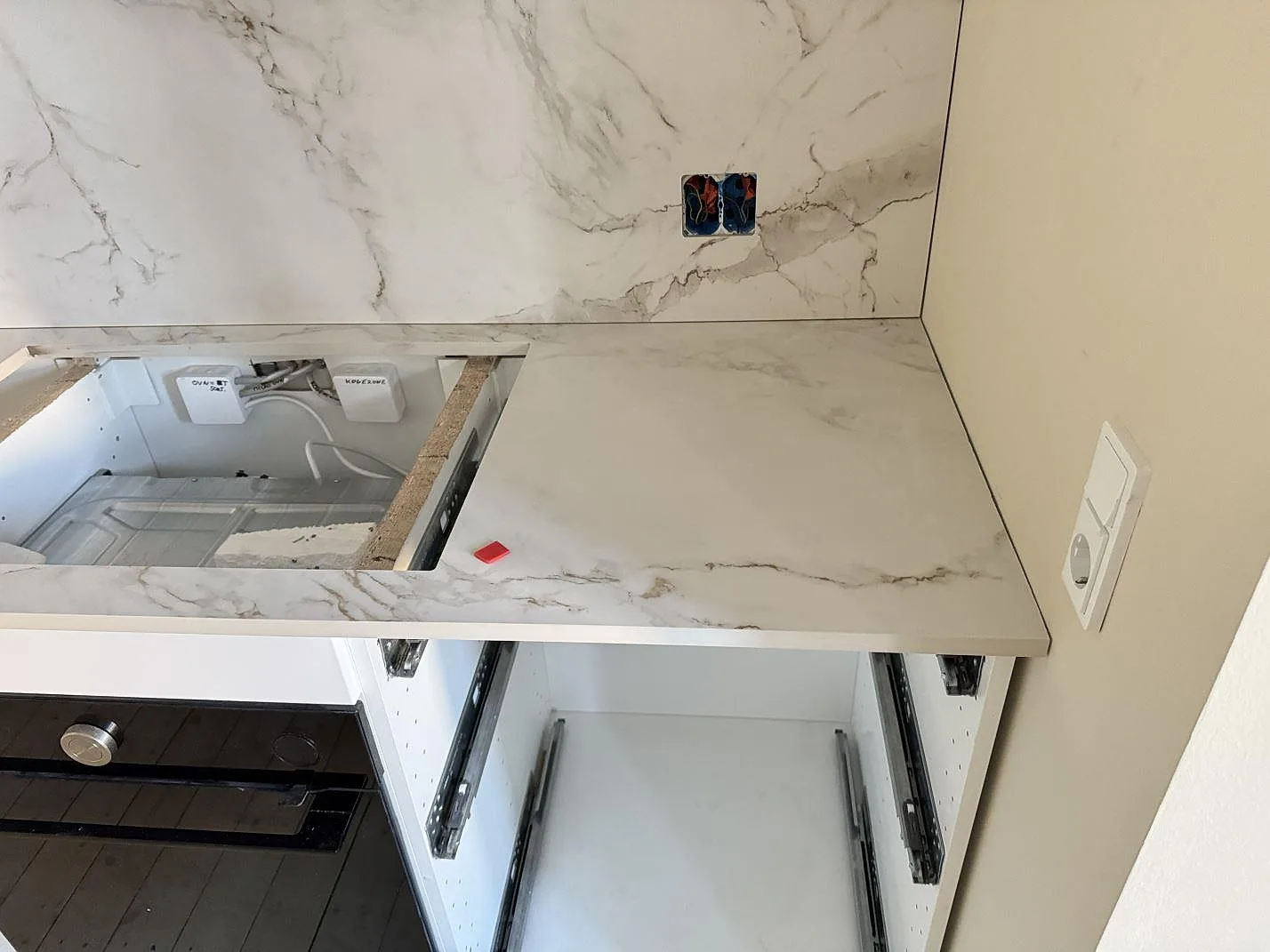 Ljus köksbänkskiva i matt Dekton Entzo med stänkskydd i samma keramik, hälluttag och öppna stommar under montering i København NV.