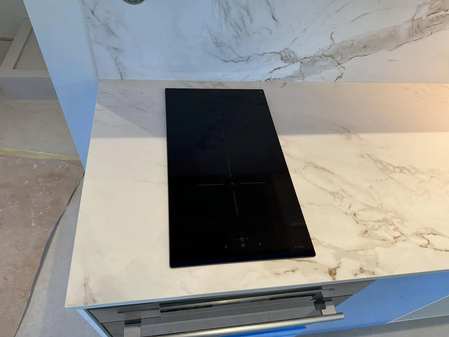 Induktionshäll infälld i en matt Dekton Entzo köksbänkskiva med matchande stänkvägg i Mölnlycke.