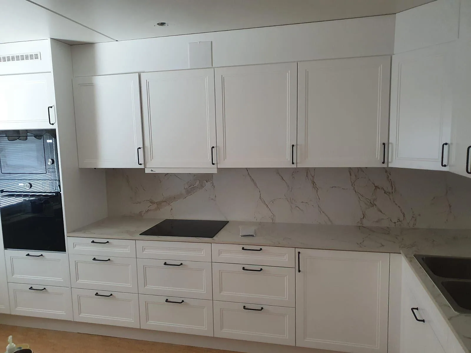 Köksbänkskiva och stänkskydd i matt Dekton Entzo med häll, vita shakerluckor och rostfri diskho i Rönninge.