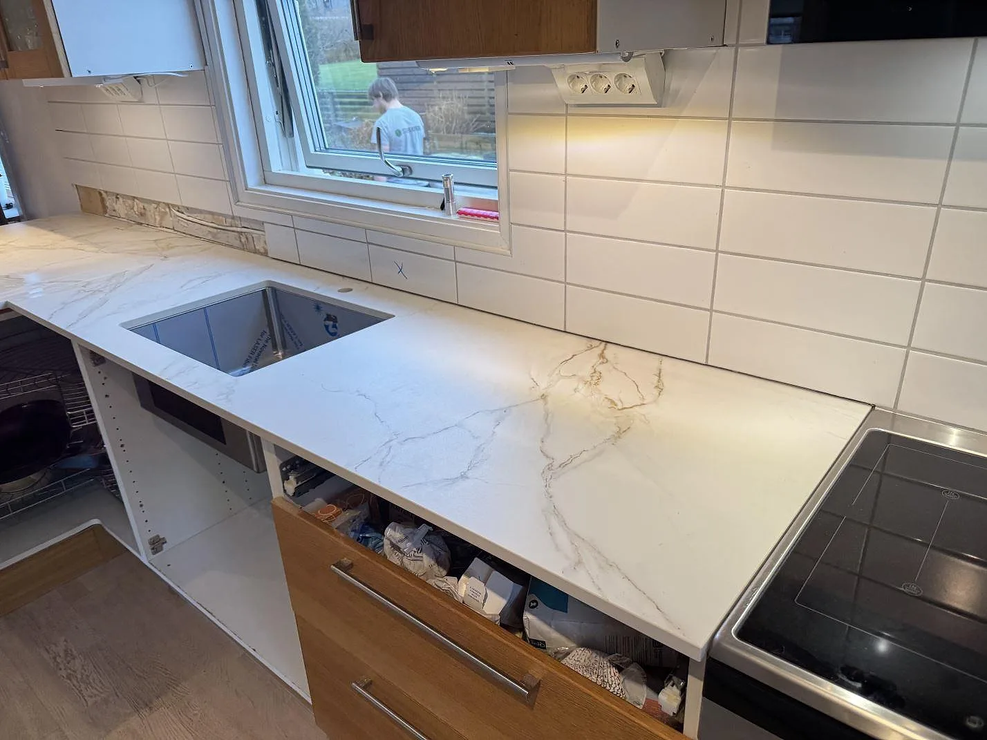 Köksbänkskiva i matt Dekton Entzo med synlig diskho, blandare och fristående spis i ett kök i Sätila.