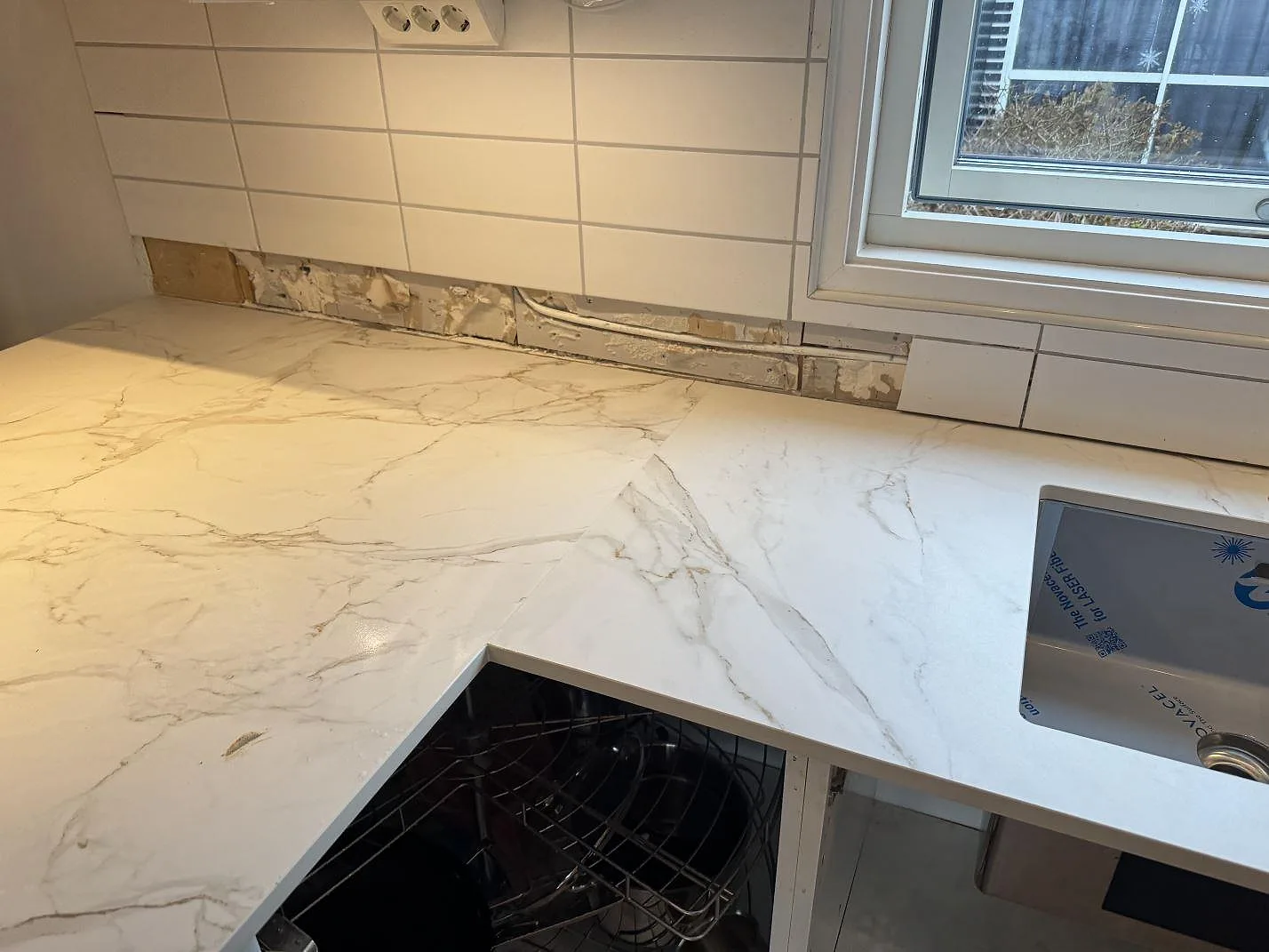 Detalj av matt Dekton Entzo runt diskzonen, med marmorlik ådring och kakelvägg under montering i Sätila.
