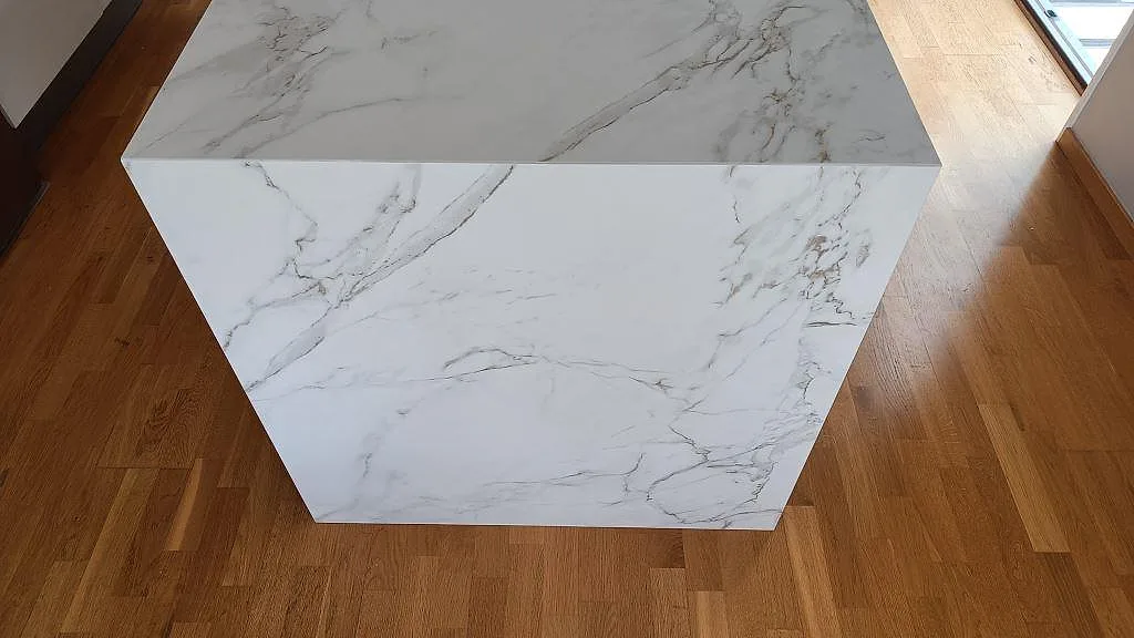 Gavelvy av köksö med matt Dekton Entzo på ovansida och gavel, vit keramik med grå ådring i Staffanstorp.