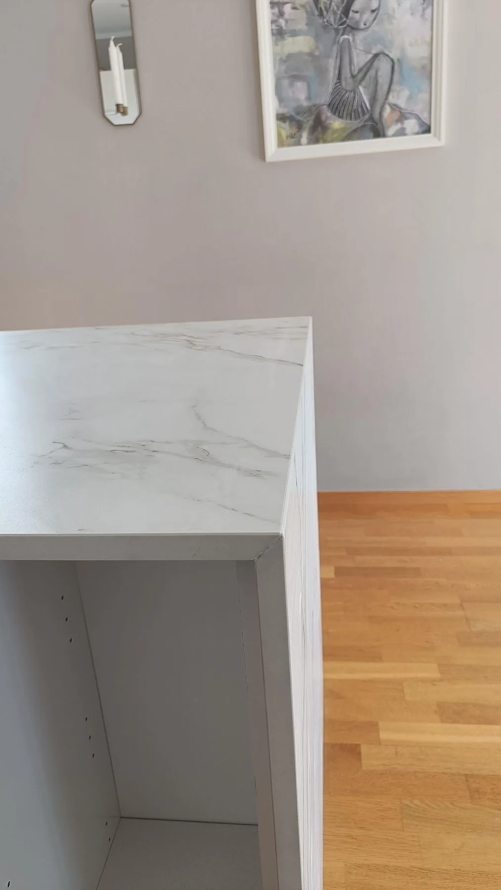 Detalj av kant och gavel på köksö i matt Dekton Entzo, monterad mot öppna stommar i ett kök i Staffanstorp.