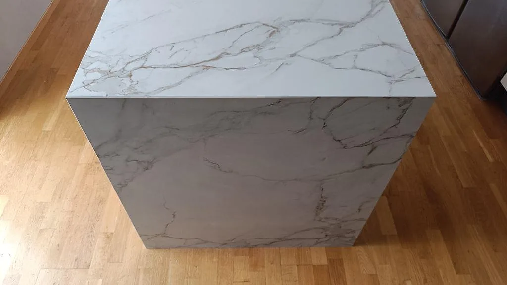 Ovanifrånbild av köksöns gavel i matt Dekton Entzo, med sammanhängande ljus ådring över bänkskiva och sida i Staffanstorp.