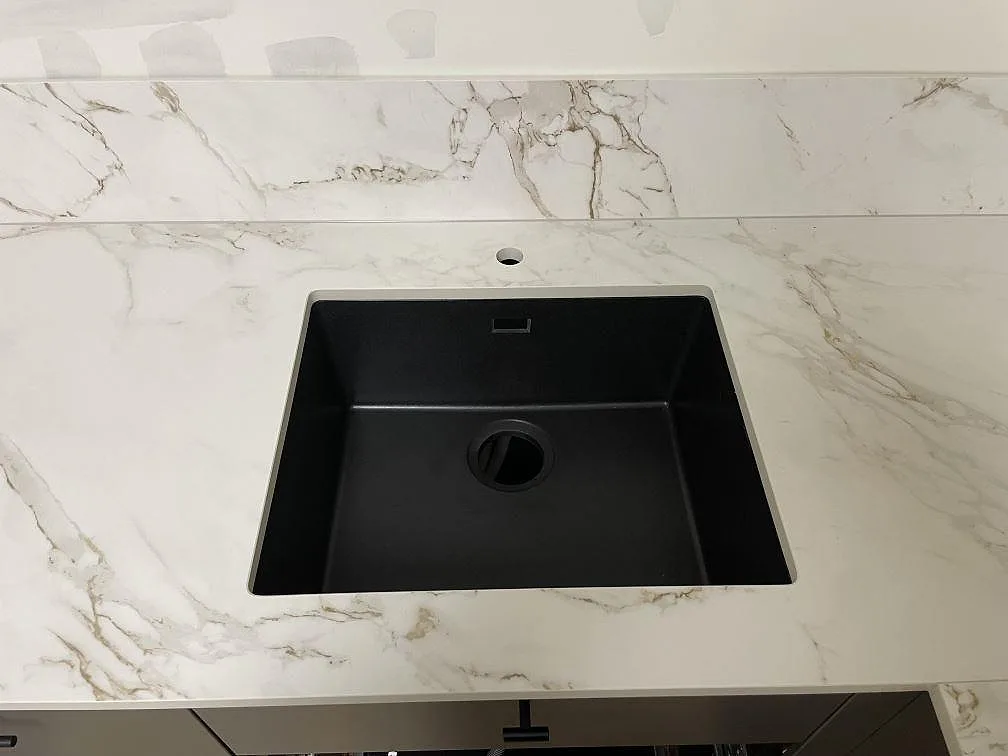 Närbild av svart diskho i en matt Dekton Entzo köksbänkskiva med matchande stänkskydd och marmorlik ådring i Stockholm.