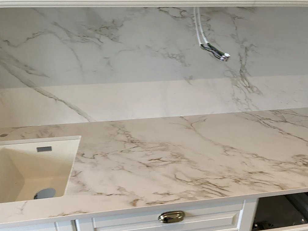 Köksbänkskiva i vit Dekton Entzo med underlimmad komposithoar och utdragbar köksblandare i ett kök i Svedala.