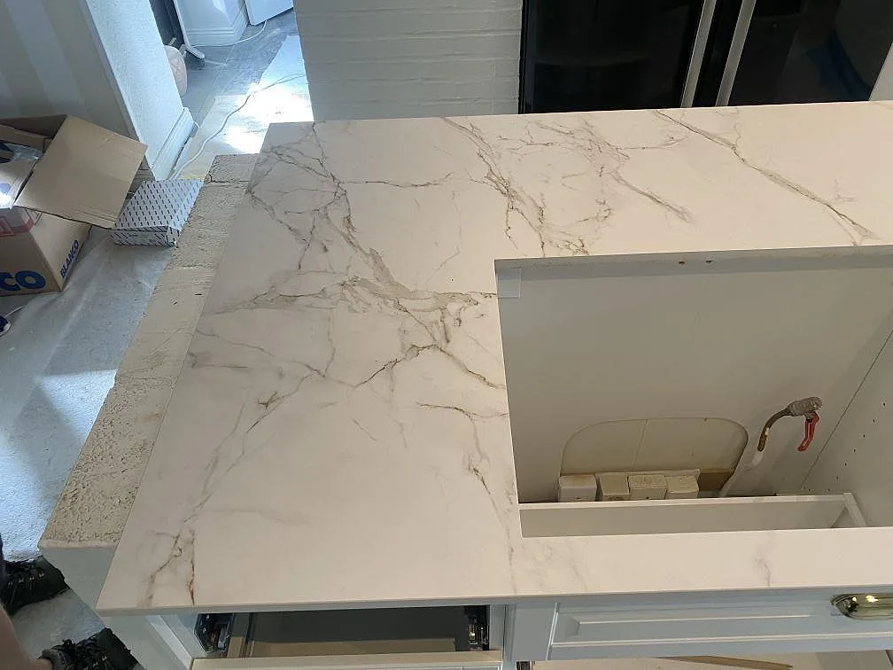 Köksö i matt vit Dekton Entzo med urtag för häll och tydlig grå ådring, fotad uppifrån i ett kök i Svedala.