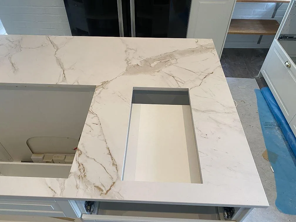 Köksö i vit Dekton Entzo med urtag för underlimmad diskho, matt yta med grå Calacatta-ådring, i ett kök i Svedala.
