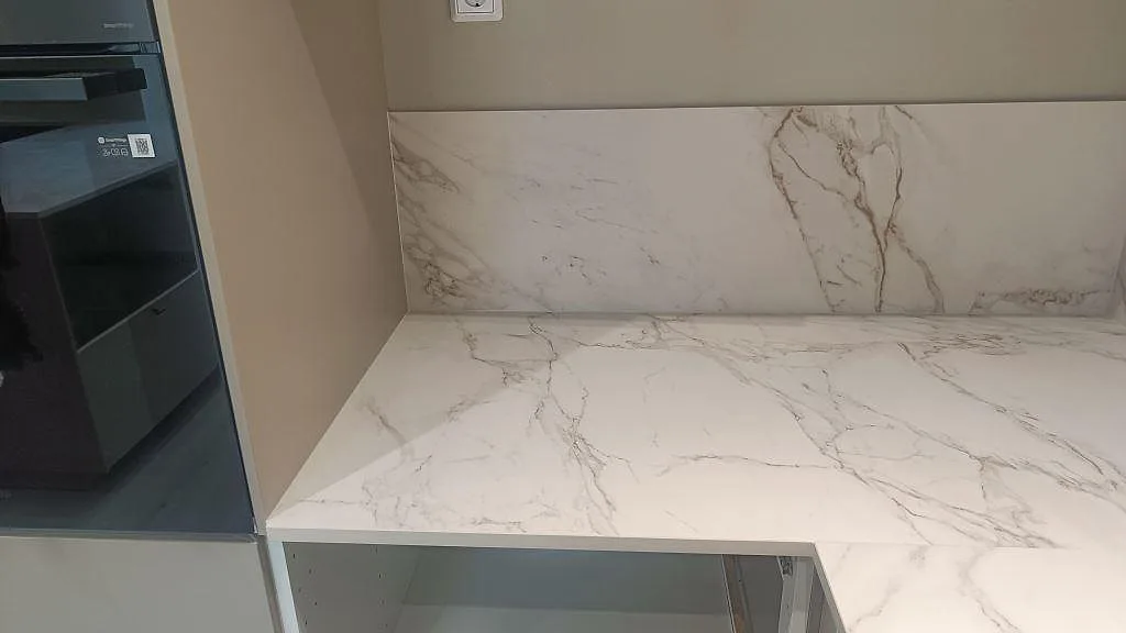 Väggbänk i matt Dekton Entzo med lågt stänkskydd bakom arbetsytan i ett kök i Trelleborg.