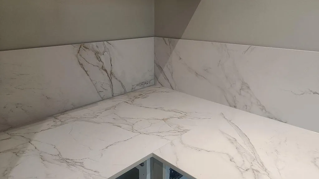 Köksbänkskiva och stänkskydd i matt Dekton Entzo med sammanhängande grå ådring i Trelleborg.