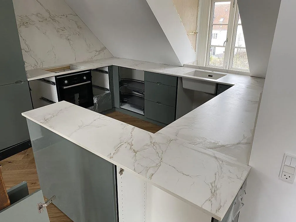 Matt köksbänkskiva i Dekton Entzo keramik med diskho, hällplats och ljus stänkyta under montering i Valby.
