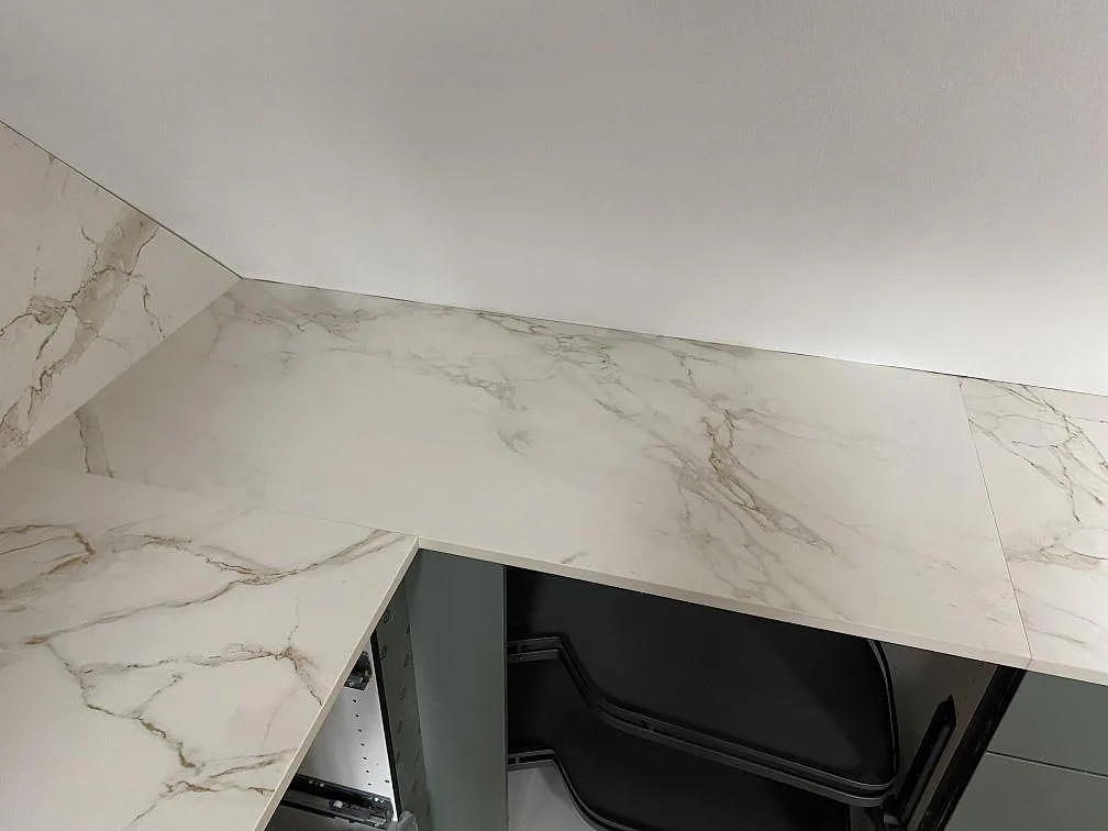 U-formad köksbänkskiva i matt Dekton Entzo keramik med ljus ådring och vägganslutning i Valby.
