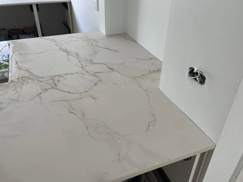 Detalj av arbetsyta i matt Dekton Entzo keramik med ljus botten, grå ådring och hällkant i ett kök i Virum.
