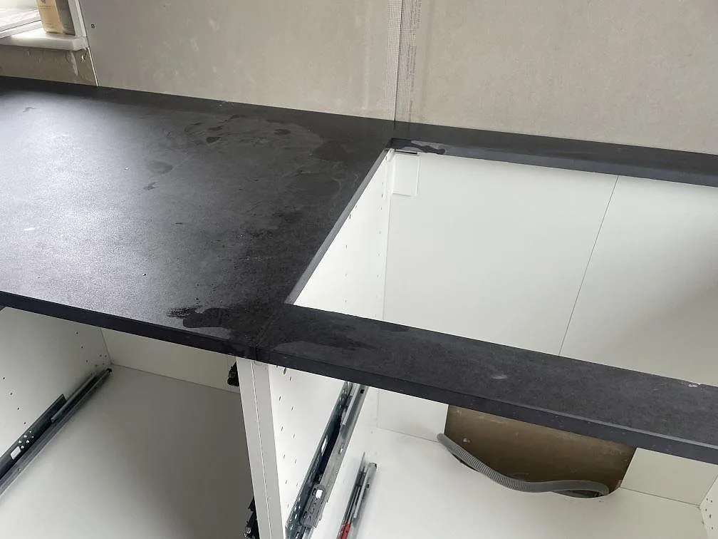 Köksbänkskiva i mörk Dekton Eter keramik, matt Mocka-finish, med förberedda urtag i ett kök under montering i Trelleborg.