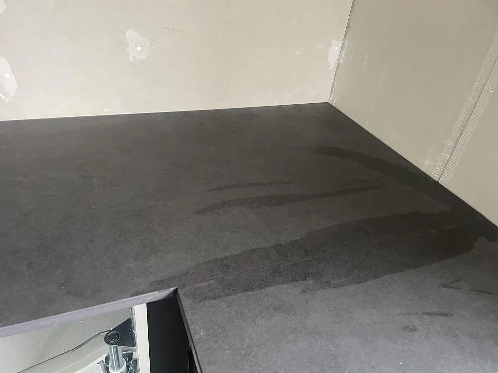 Närbild på mörk köksbänkskiva i Dekton Eter keramik med matt Mocka-yta vid kökets hörn under montering i Trelleborg.