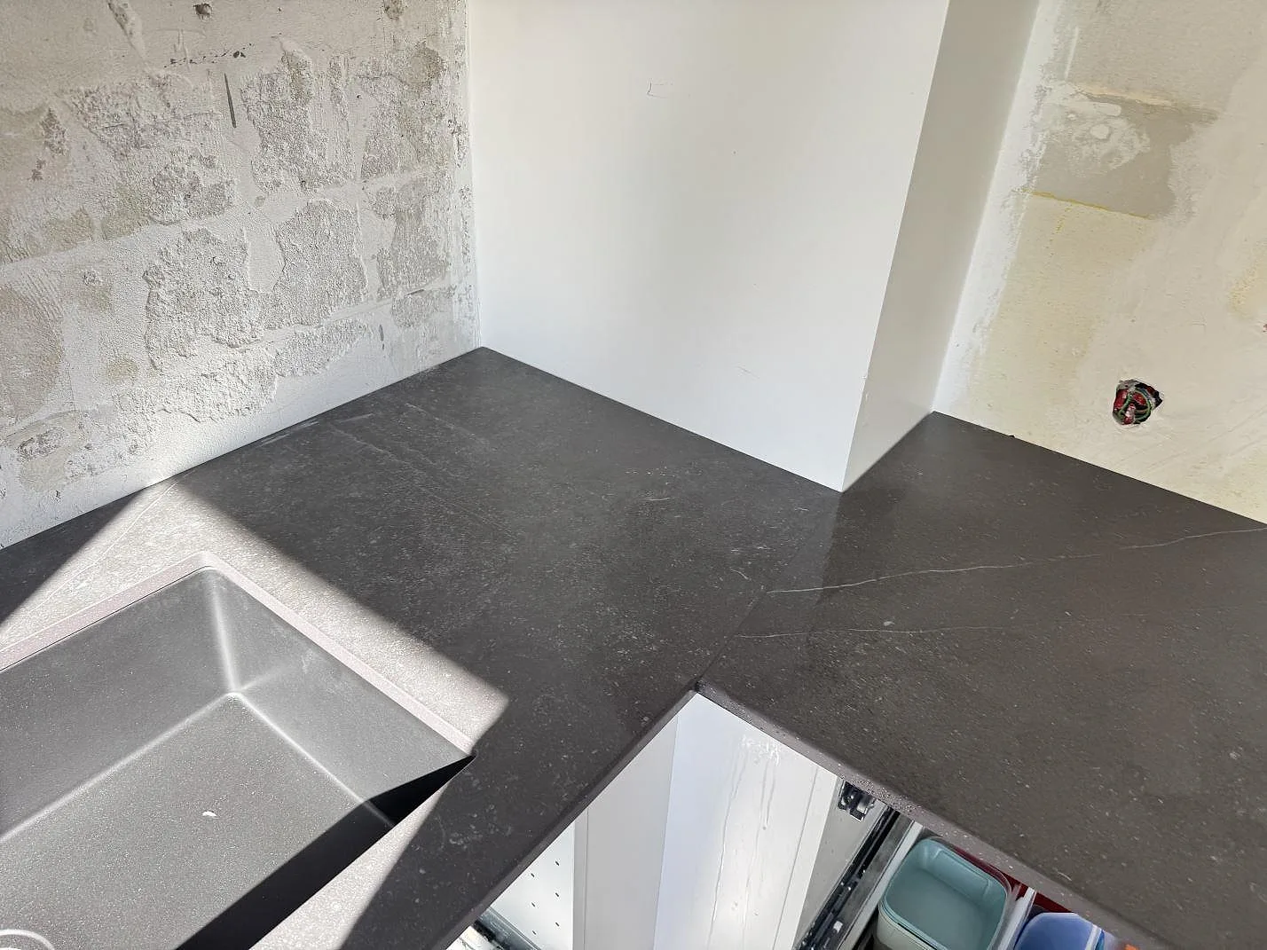 Vinkel i matt Dekton Fossil köksbänkskiva med svart diskho och mörkgrå stenstruktur i Arlöv.