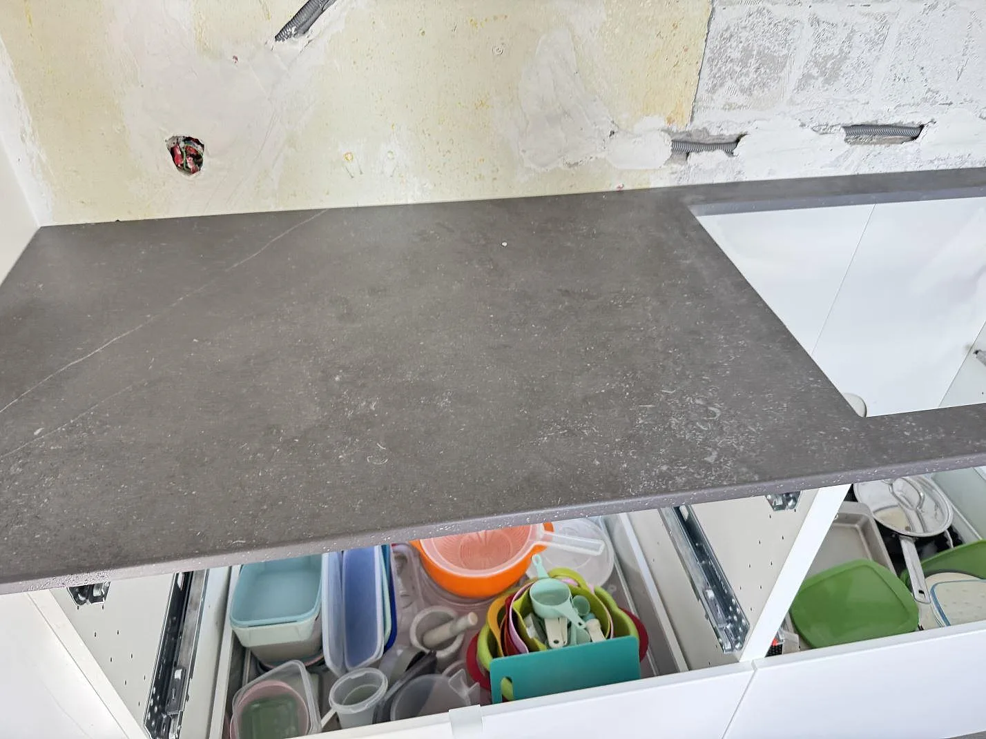Rak arbetsyta i matt Dekton Fossil keramik ovan öppna vita köksstommar i Arlöv.