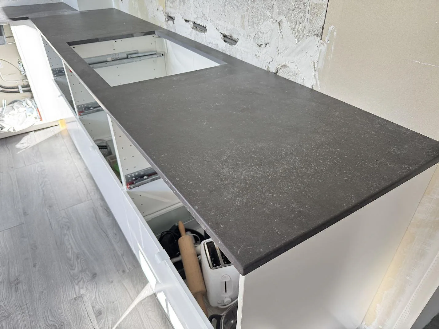 Matt köksbänkskiva i mörkgrå Dekton Fossil keramik med lång arbetsyta och förberedd öppning i ett kök i Arlöv.