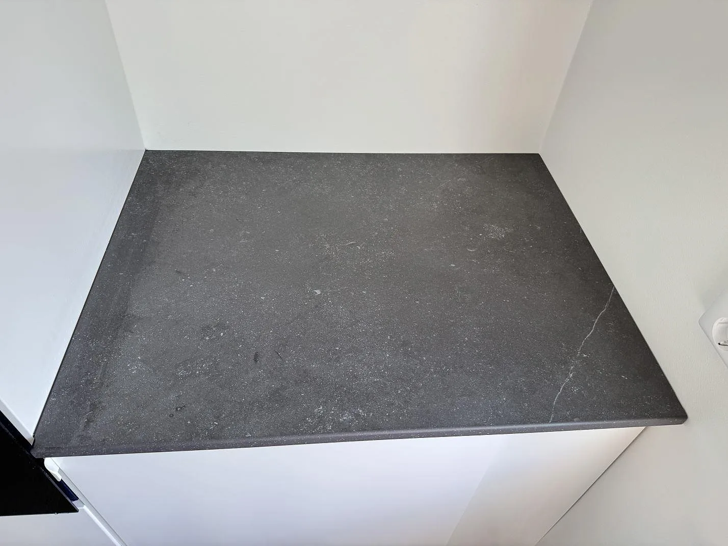Närbild av mörkgrå matt Dekton Fossil bänkskiva med diskret mönstring på kort köksdel i Arlöv.