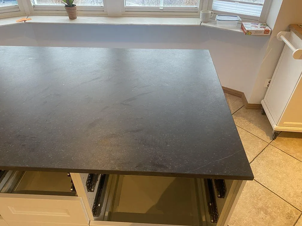 Köksö i mörk matt Dekton Fossil sedd från sidan med kakelgolv i ett kök i Bara.