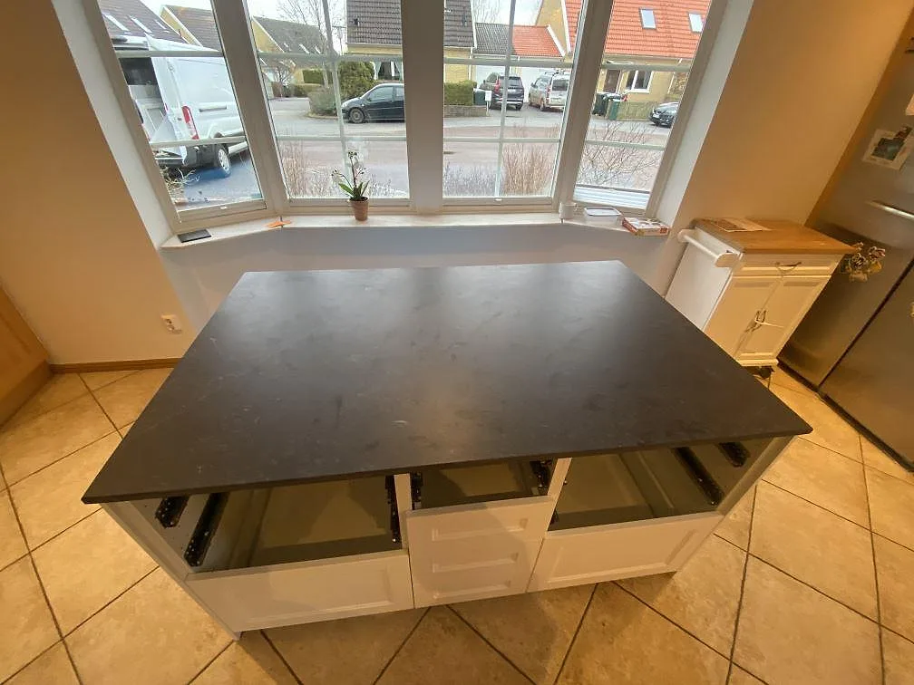 Köksö i Dekton Fossil, matt mörk greige keramik, monterad framför ett burspråk i ett kök i Bara.