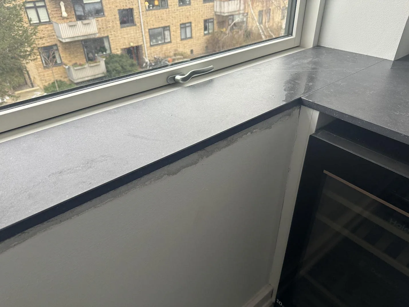 Fönsterbänk och L-formad bänkskiva i matt Dekton Fossil vid stort fönster i Hellerup.