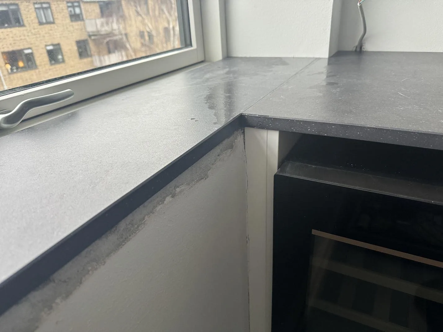 Närbild av hörnskarv i matt Dekton Fossil mellan fönsterbänk och köksbänkskiva i Hellerup.