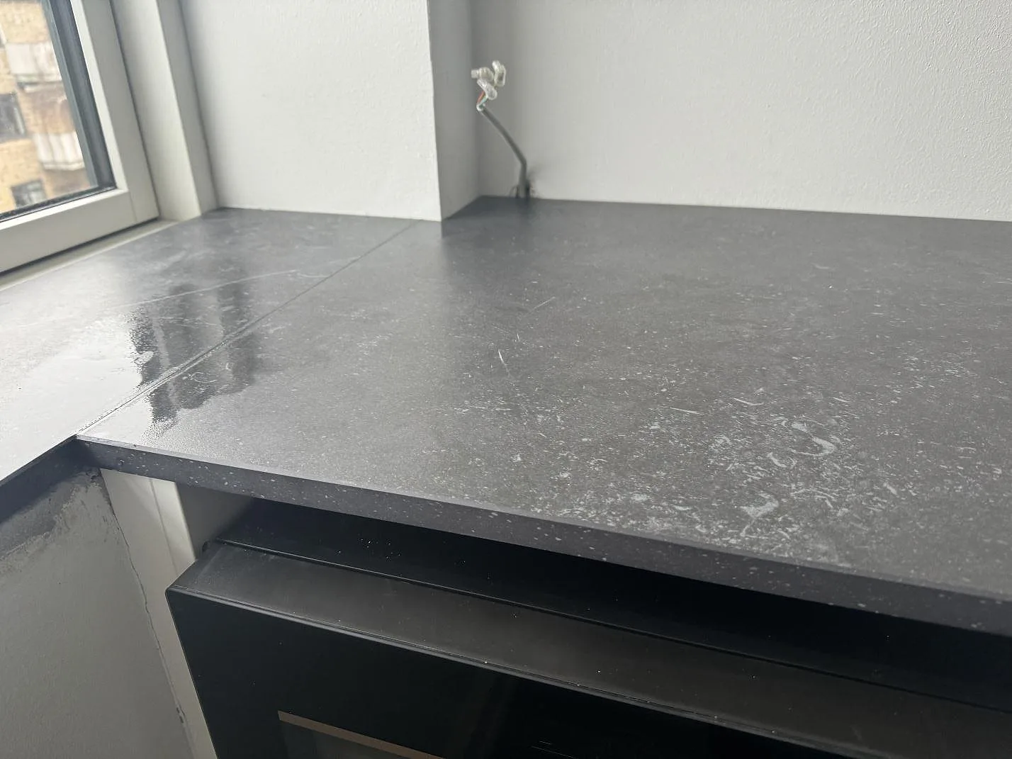 Detalj av matt Dekton Fossil med grå struktur, 20 mm kant och fönsterljus i ett kök i Hellerup.