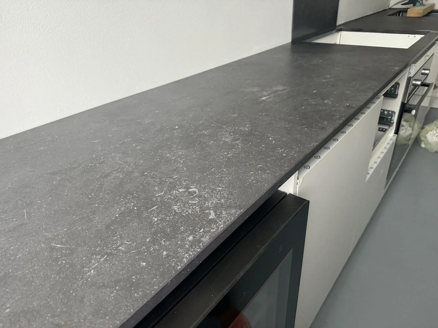Lång köksbänkskiva i matt Dekton Fossil med vit köksinredning och synlig kant i Hellerup.