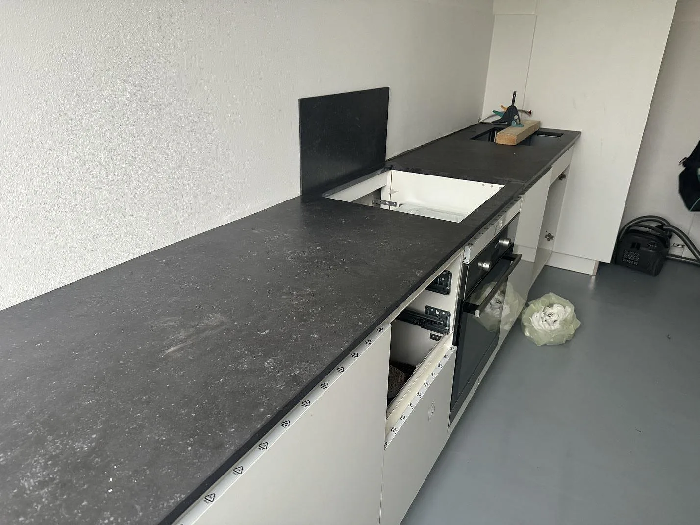 Köksbänkskiva i matt Dekton Fossil med öppningar för diskho och häll i ett kök under montering i Hellerup.