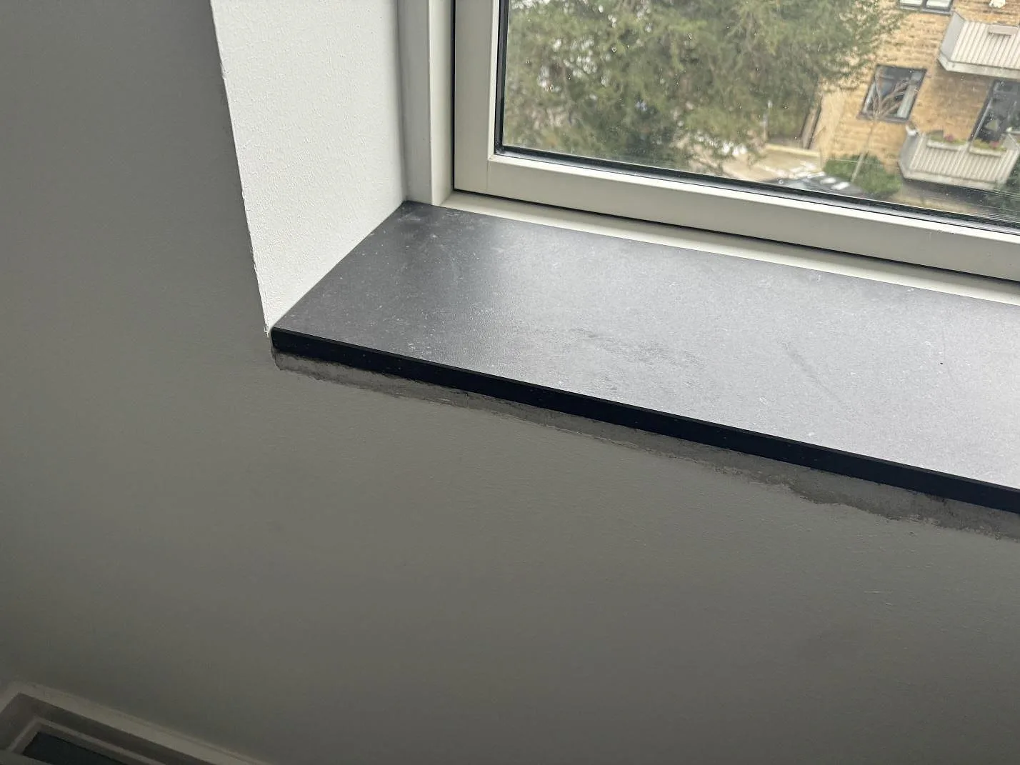 Fönsterbänk i matt Dekton Fossil med mörk kant och stort fönster i Hellerup.