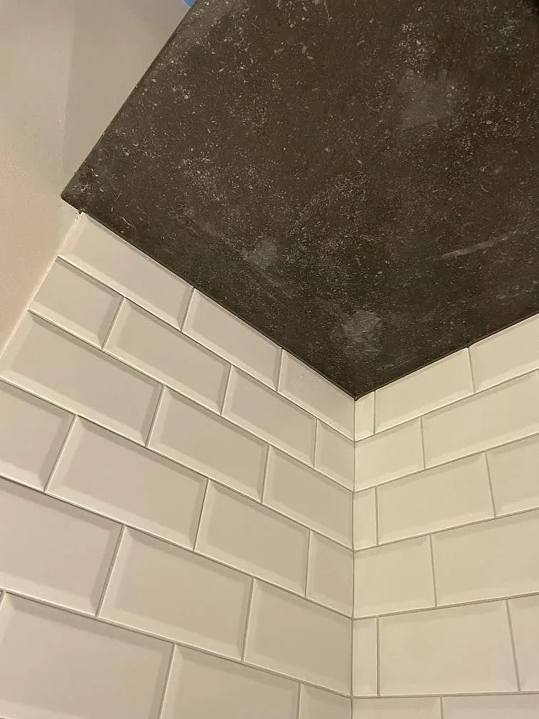 Övermonterad induktionshäll infälld i matt Dekton Fossil köksbänkskiva mot vitt kakel i Höllviken.
