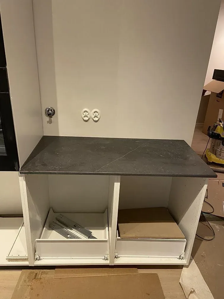 Köksbänkskiva i Dekton Fossil ovanpå vita köksstommar under montering i Höllviken.