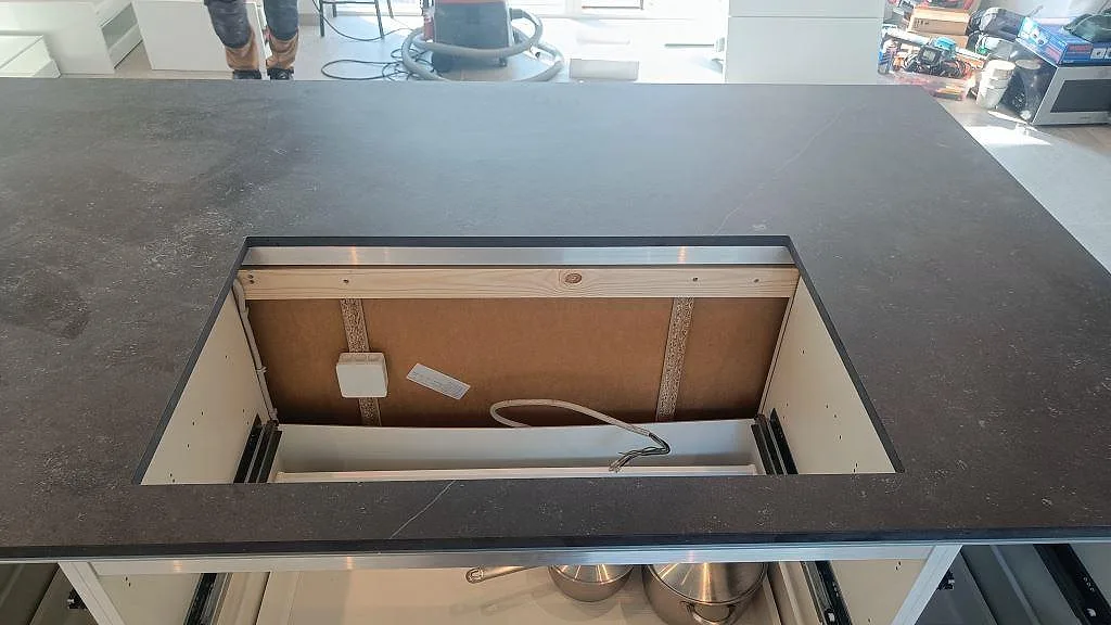 Närbild på hällurtag i en köksö av matt Dekton Fossil keramik med mörk bänkskiva i Jyllinge.