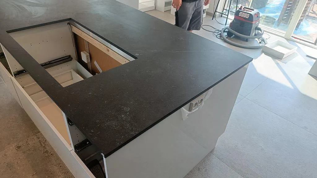 Köksö i matt Dekton Fossil keramik med mörk yta, tunn kant och förberett urtag under montering i Jyllinge.