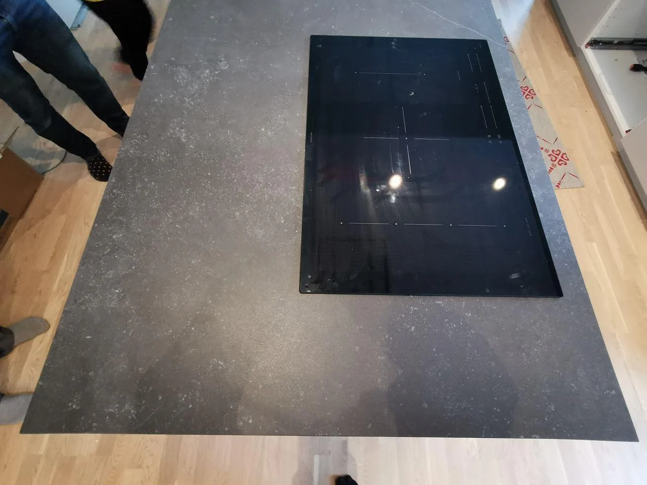 Köksö i mörk Dekton Fossil ovanifrån med en övermonterad induktionshäll under montering i ett kök i Landvetter.
