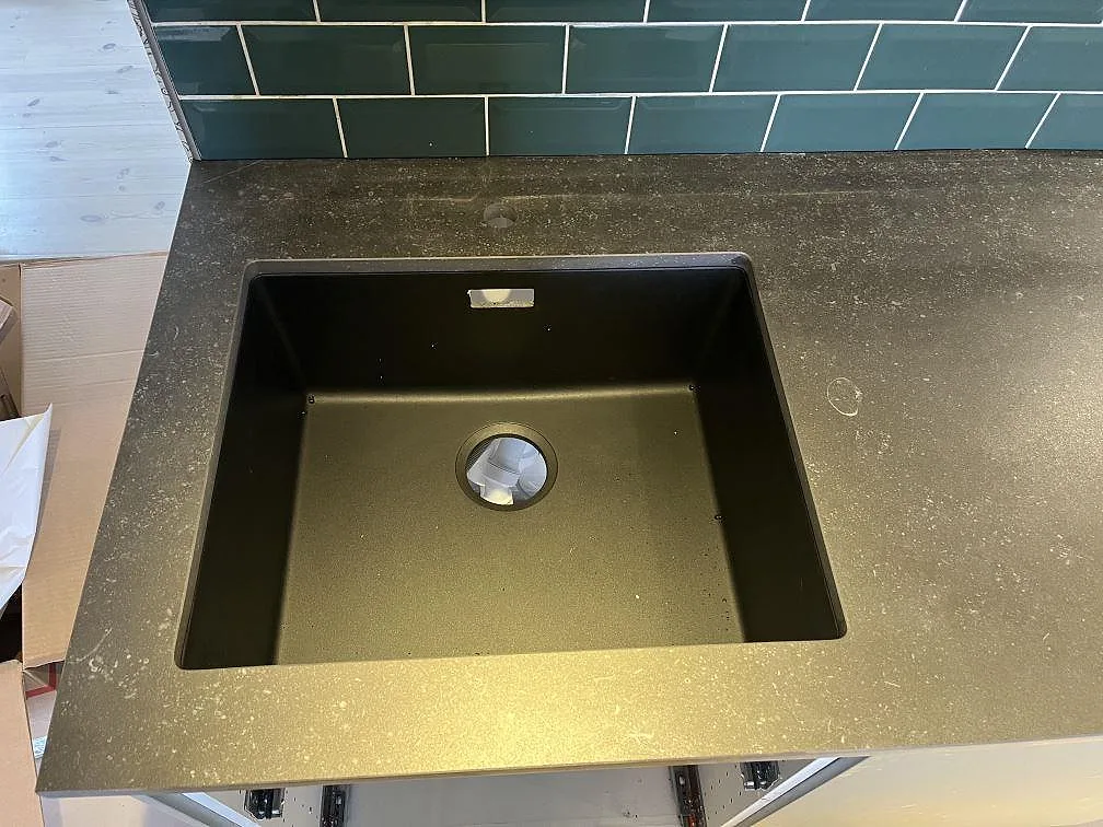 Underlimmad svart kompositdiskho infälld i en köksbänkskiva i Dekton Fossil keramik i ett kök i Timmele.